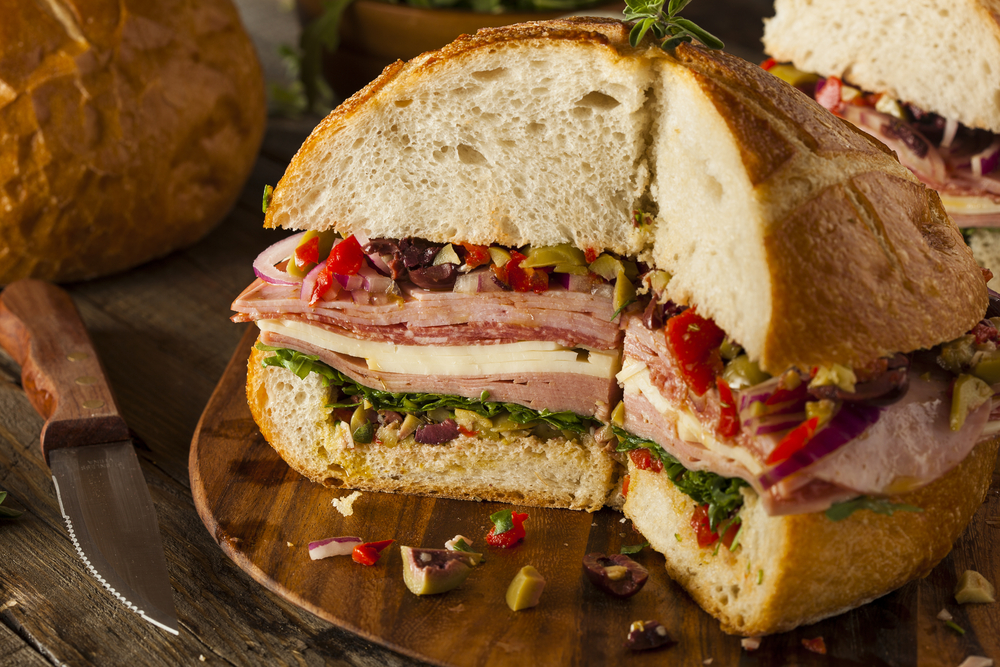 Muffaletta sandwich with meat, olives, and cheese on a cutting board