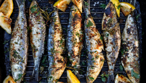 Overhead view of grilled sardines and lemons.