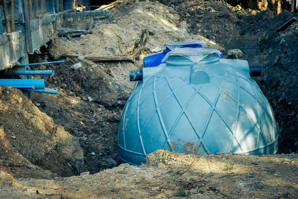 Plastic septic holding tank surrounded by dug up dirt.