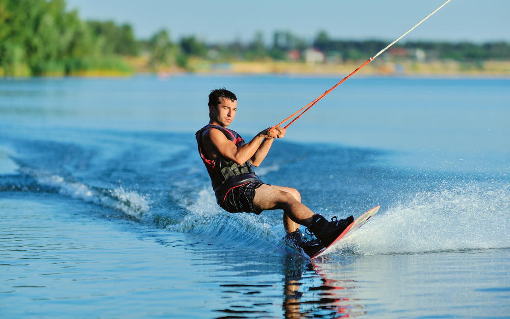Wakeboarder on a lake with trees in the background.