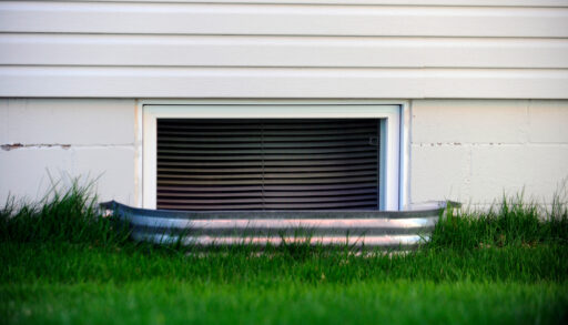 Exterior view of a basement window well in the spring.