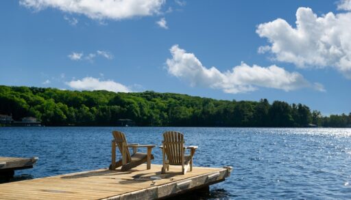 Muskoka chairs on a dock overlooking a lake.