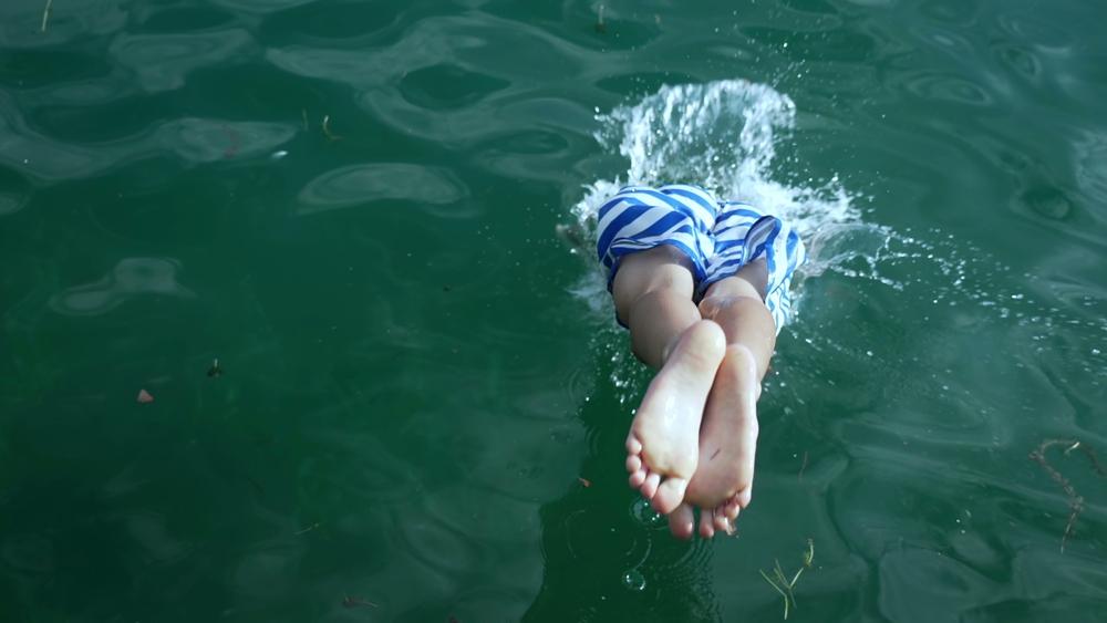 Back of young boy diving into water