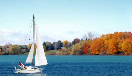 Sailboat with a Canadian flag on lake.