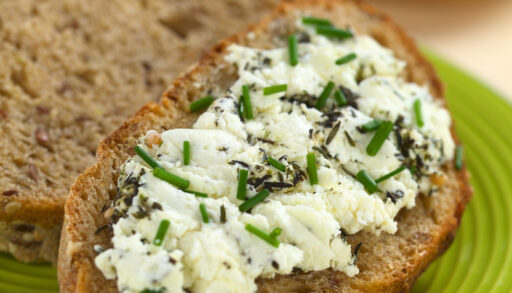 Goat cheese sprinkled with chives spread on wholegrain bread.