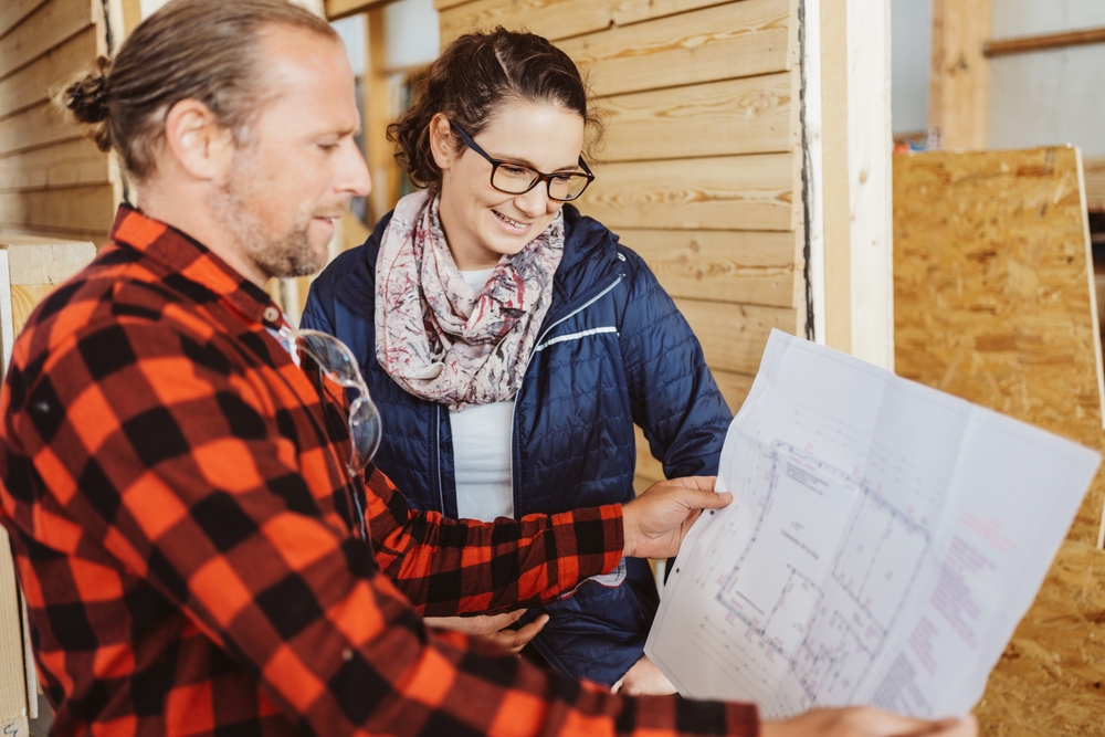 Male contractor going over building plans with a female homeowner.