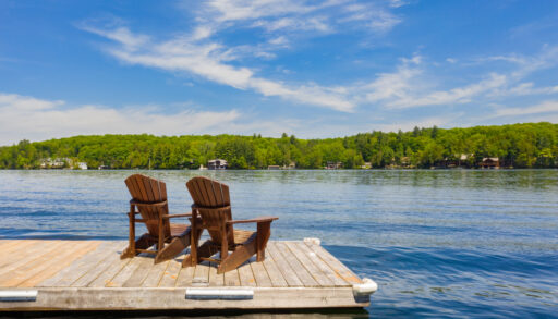 Two Muskoka chairs on a dock looking out over the water.