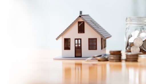Small house on a table next to a jar of coins.