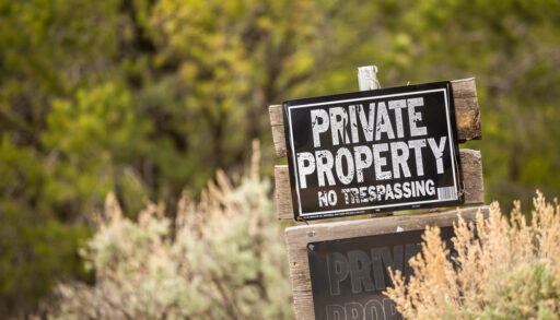 Private property and no trespassing sign in a field.