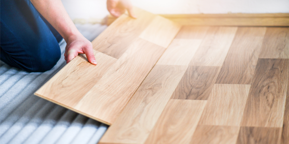 Person laying laminate flooring.
