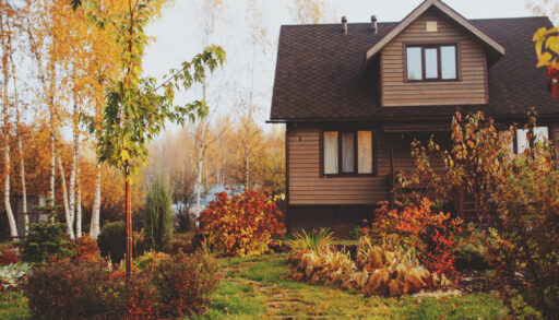 Small cottage near a lake surrounded by fall foliage.