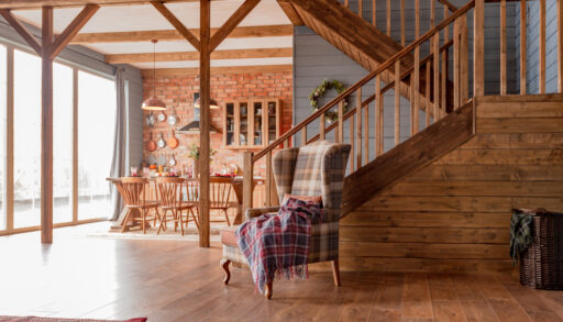 Interior of a cabin living room with a staircase and armchair.