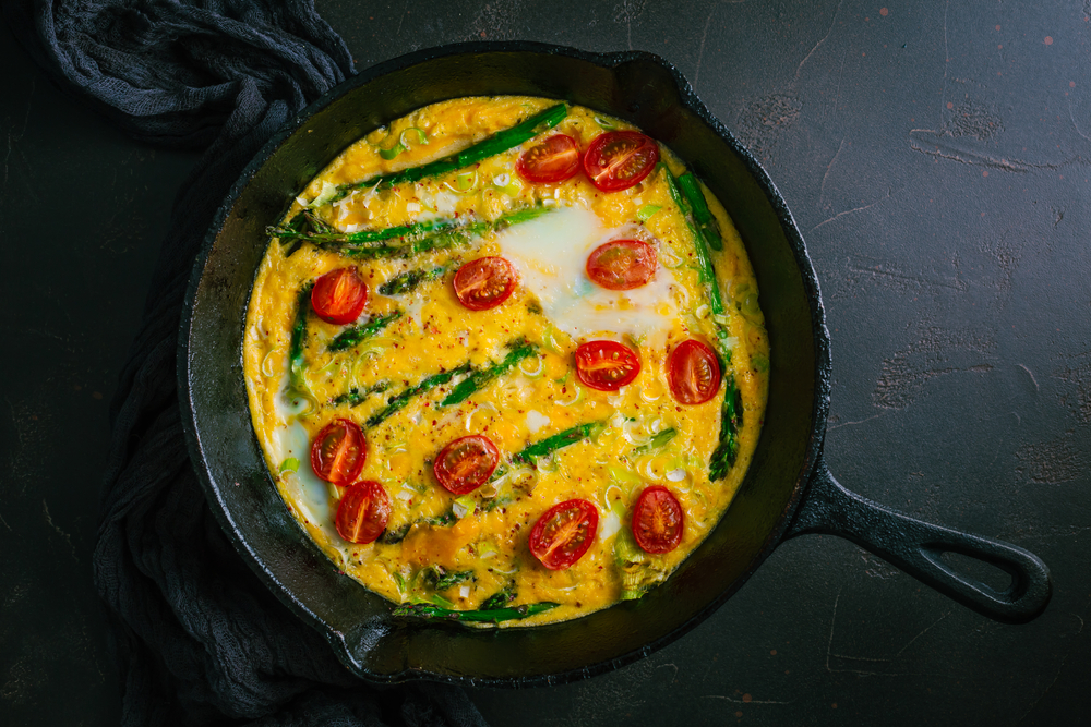 Overhead view of an asparagus frittata with cherry tomatoes.