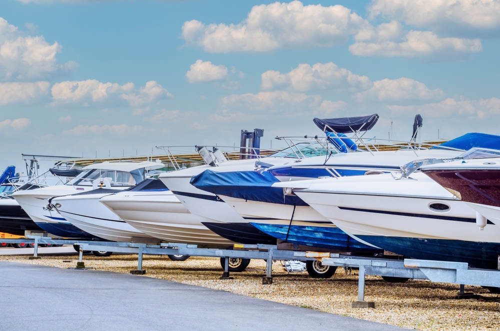 Row of new boats lined up along a paved road.
