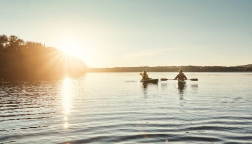People kayaking on a lake at sunset.