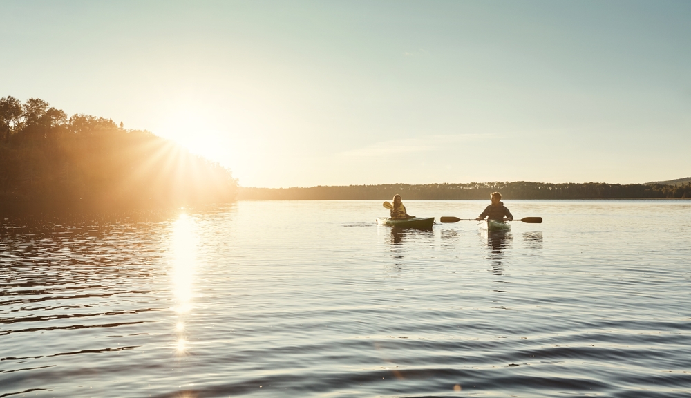 People kayaking on a lake at sunset.