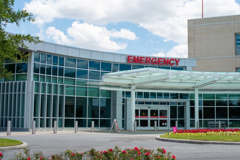 Red emergency sign on a glass hospital building.