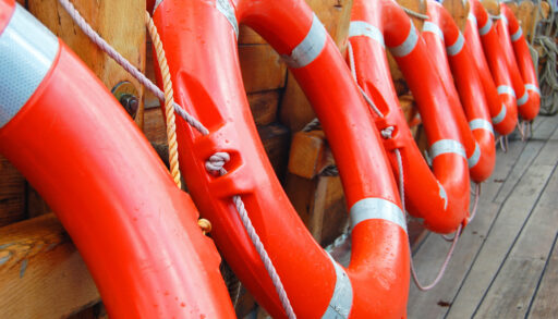 Row of orange life preservers on a boat deck.