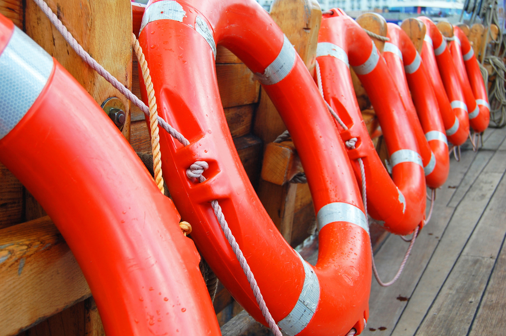 Row of orange life preservers on a boat deck.