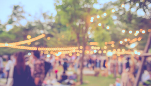 Blurred photo of a summer festival with string lights hung in the trees.