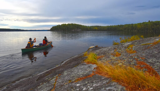 Two people in a canoe paddle Cirrus Lake in Quetico Provincial Park, Ontario.