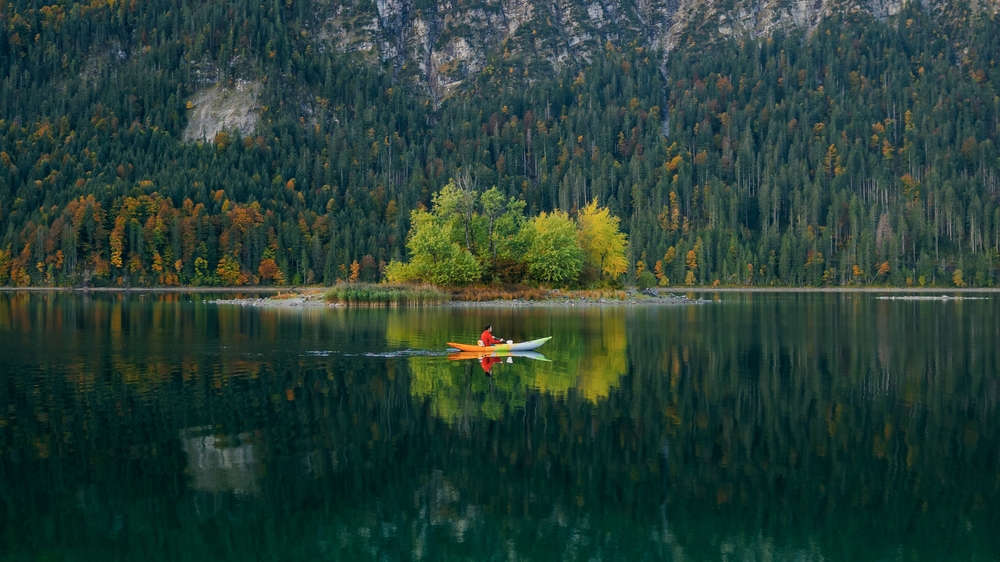 Man kayaking on a lake in autumn.