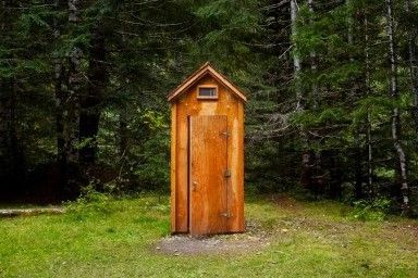 What materials should I use when building the pit walls of my outhouse?