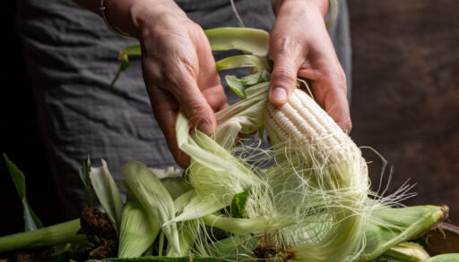Woman shucking white corn.