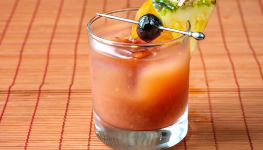 Bermudian rum swizzle cocktail on a red table.