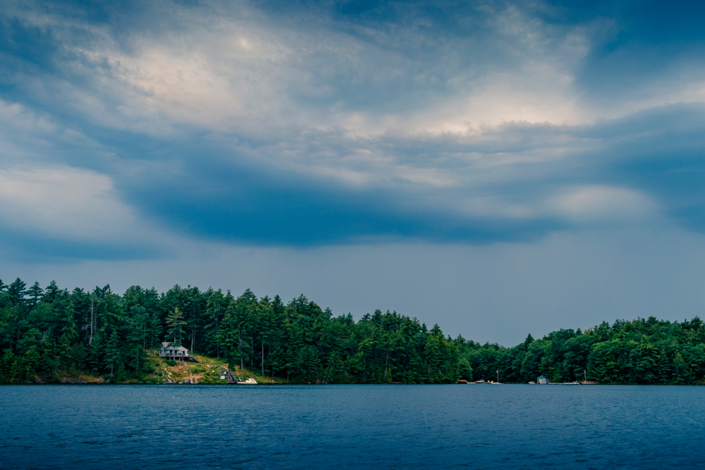 View of storm clouds forming over a lake and cottage.