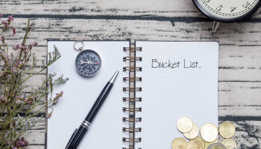 Notebook on a wooden table with a pen and a compass.