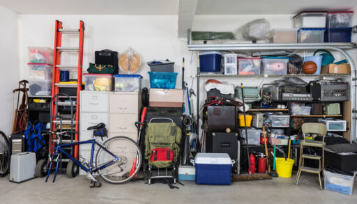 Garage filled with various items like a ladder, bike, cooler and yard supplies.
