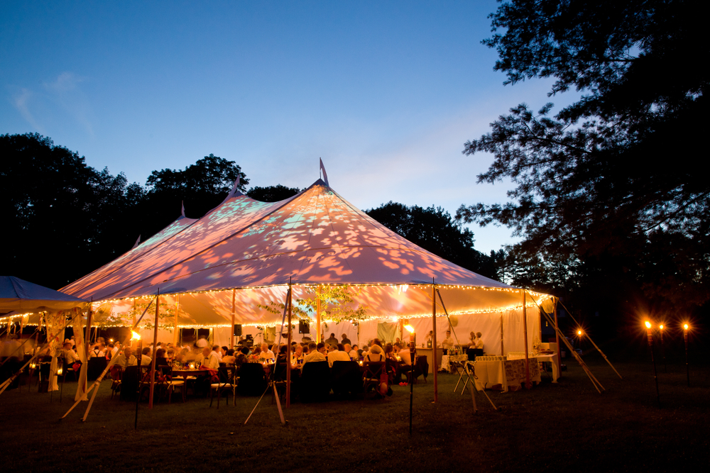 Special event tent lit up from the inside with dark blue night time sky and trees