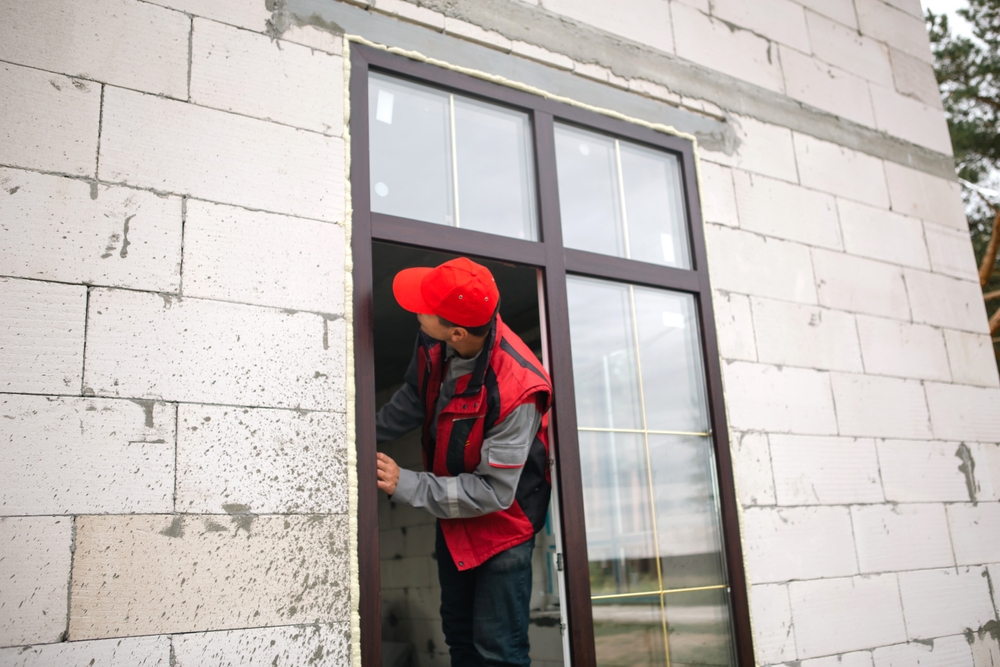 Man in a red vest checking a window after installation.