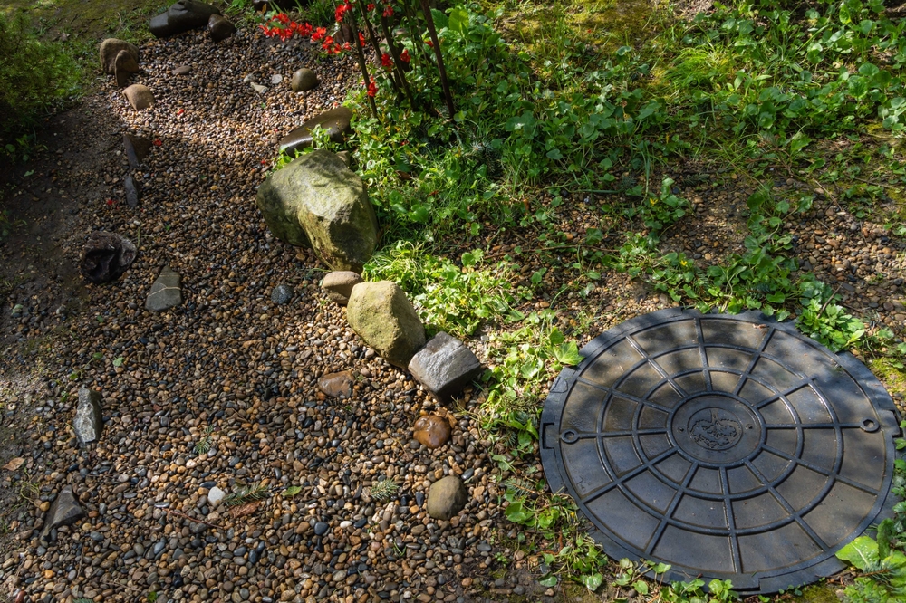 Overhead view of the drainage cover of a septic tank in a forest.