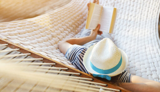 Person laying in a hammock reading a book.