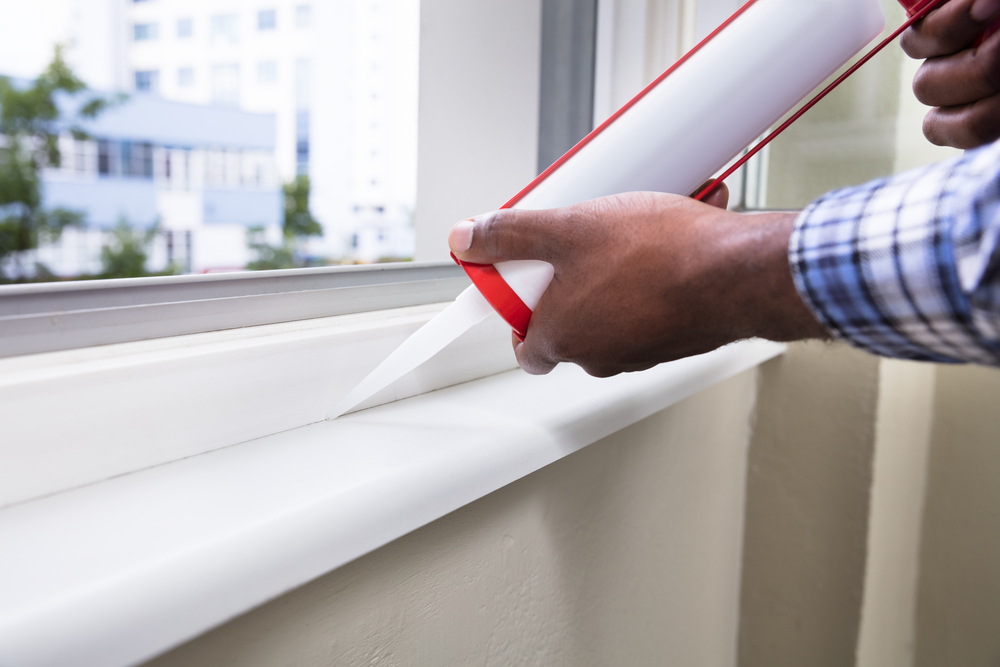 Man applying caulking to a window.