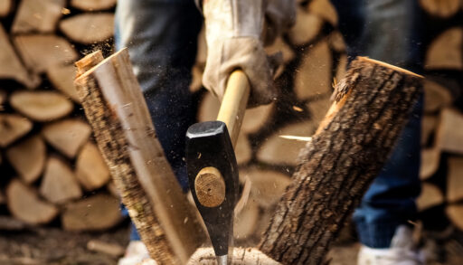 Person using an axe to split a piece of wood.