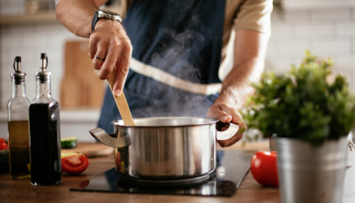 Man stirring a pot on a stove.