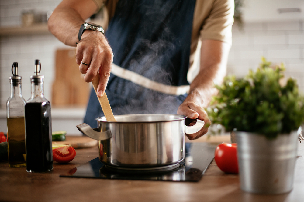 Man stirring a pot on a stove.