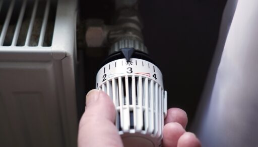 Person turning the thermostat dial on a radiator.
