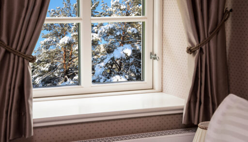 Curtains pulled back from a window with a winter landscape.