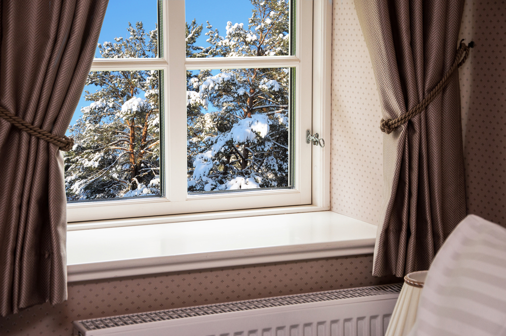 Curtains pulled back from a window with a winter landscape.