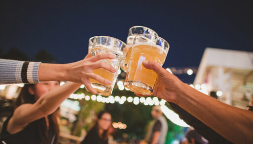 Three people raising their beer glasses together.