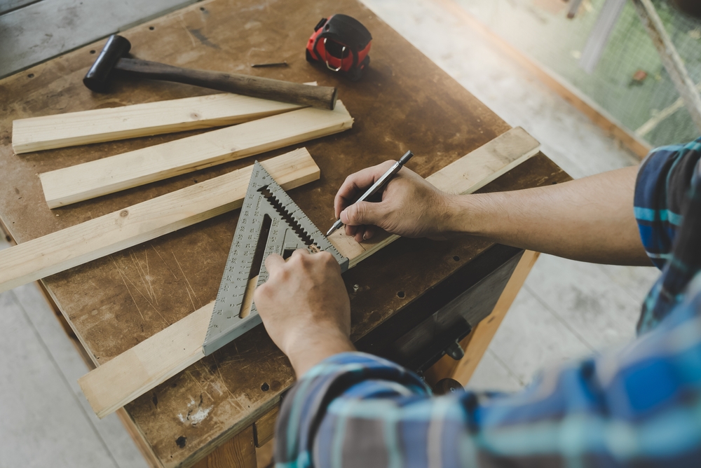 Person measuring small pieces of wood on a workbench.