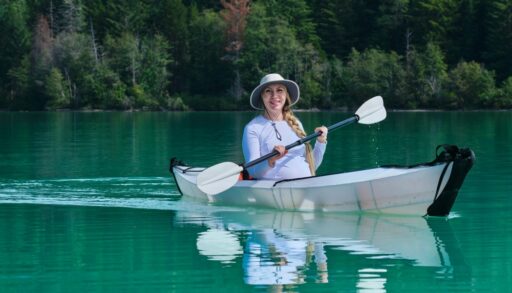 Woman on a lake in a white foldable kayak.