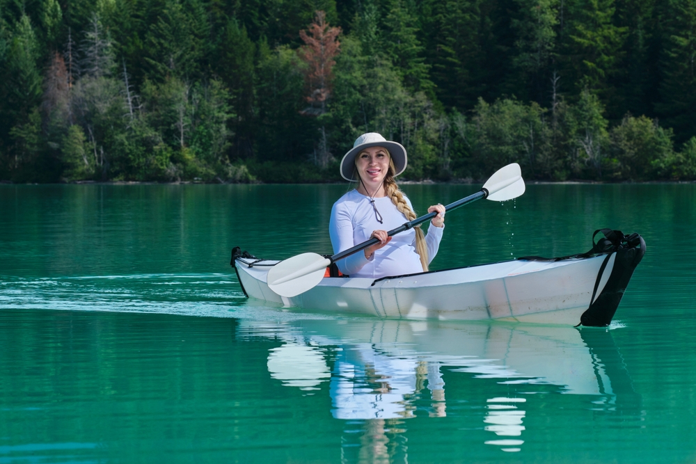 Woman on a lake in a white foldable kayak.