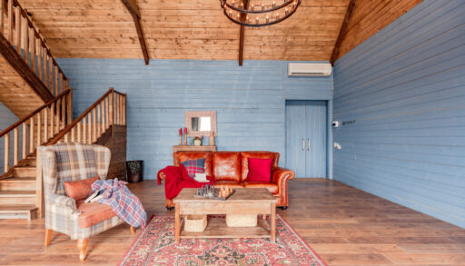 Cottage interior with blue walls, a wooden ceiling and mismatched furniture.