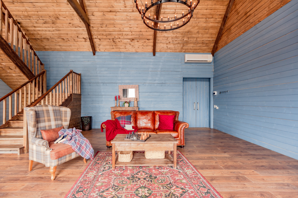 Cottage interior with blue walls, a wooden ceiling and mismatched furniture.