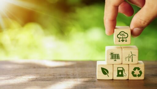 Person placing small building blocks with motifs related to reducing emissions, such as recycling or wind power.